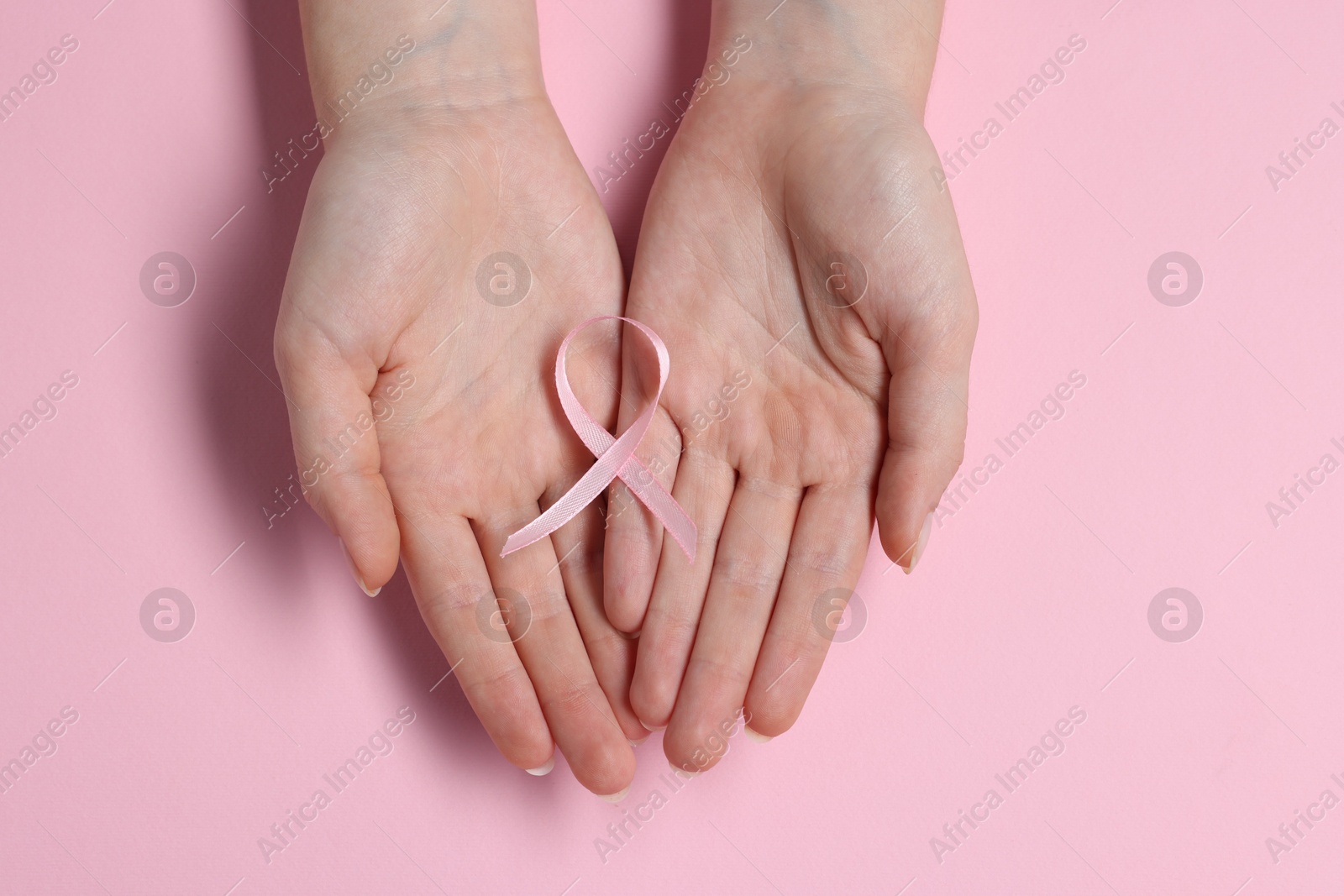 Photo of Woman with ribbon on pink background, top view. Breast cancer awareness