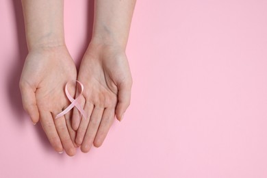 Photo of Woman with ribbon on pink background, top view and space for text. Breast cancer awareness