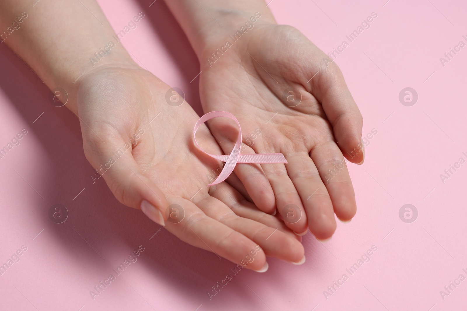 Photo of Woman with ribbon on pink background, closeup. Breast cancer awareness