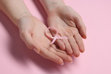 Photo of Woman with ribbon on pink background, closeup. Breast cancer awareness