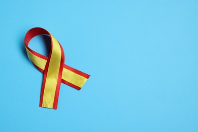 Photo of One yellow and red ribbon on light blue background, top view with space for text. Hepatitis C awareness