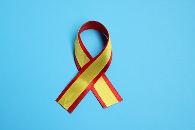 One yellow and red ribbon on light blue background, top view. Hepatitis C awareness