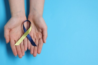 Photo of Woman with colorful ribbon on light blue background, top view and space for text. Down syndrome awareness