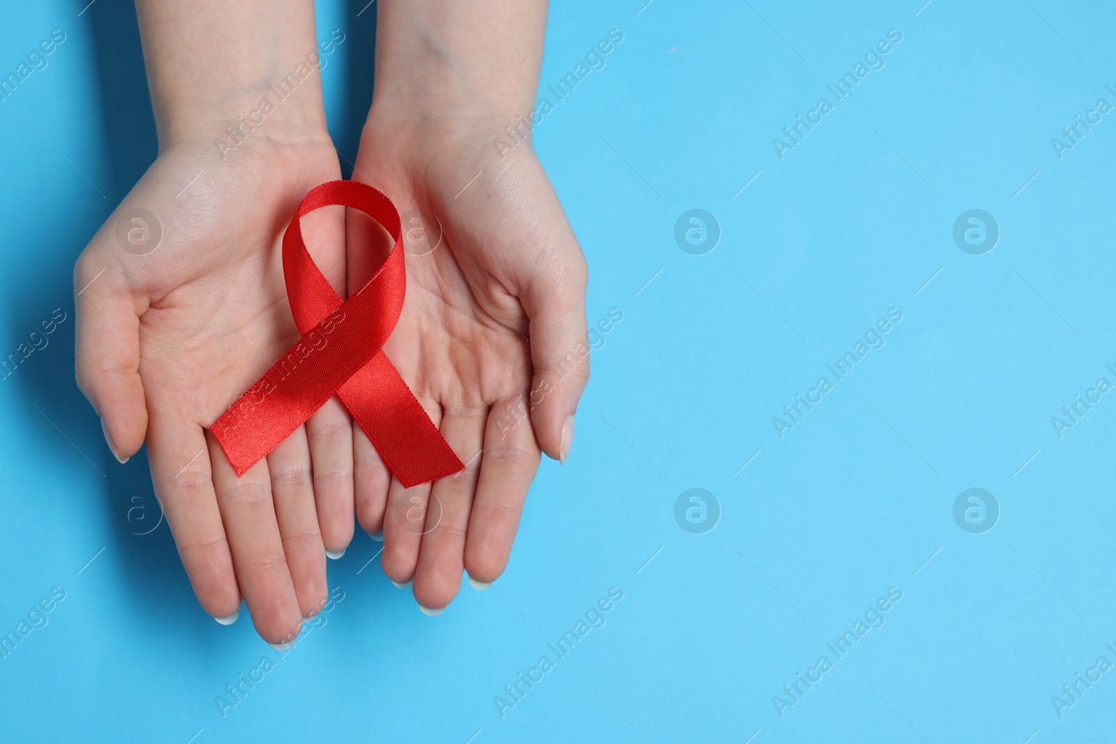 Photo of Woman with red ribbon on light blue background, top view and space for text. HIV (AIDS) disease awareness