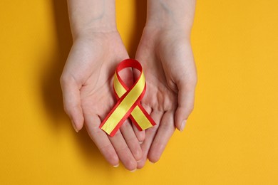 Photo of Woman with colorful ribbon on yellow background, top view. Hepatitis C awareness