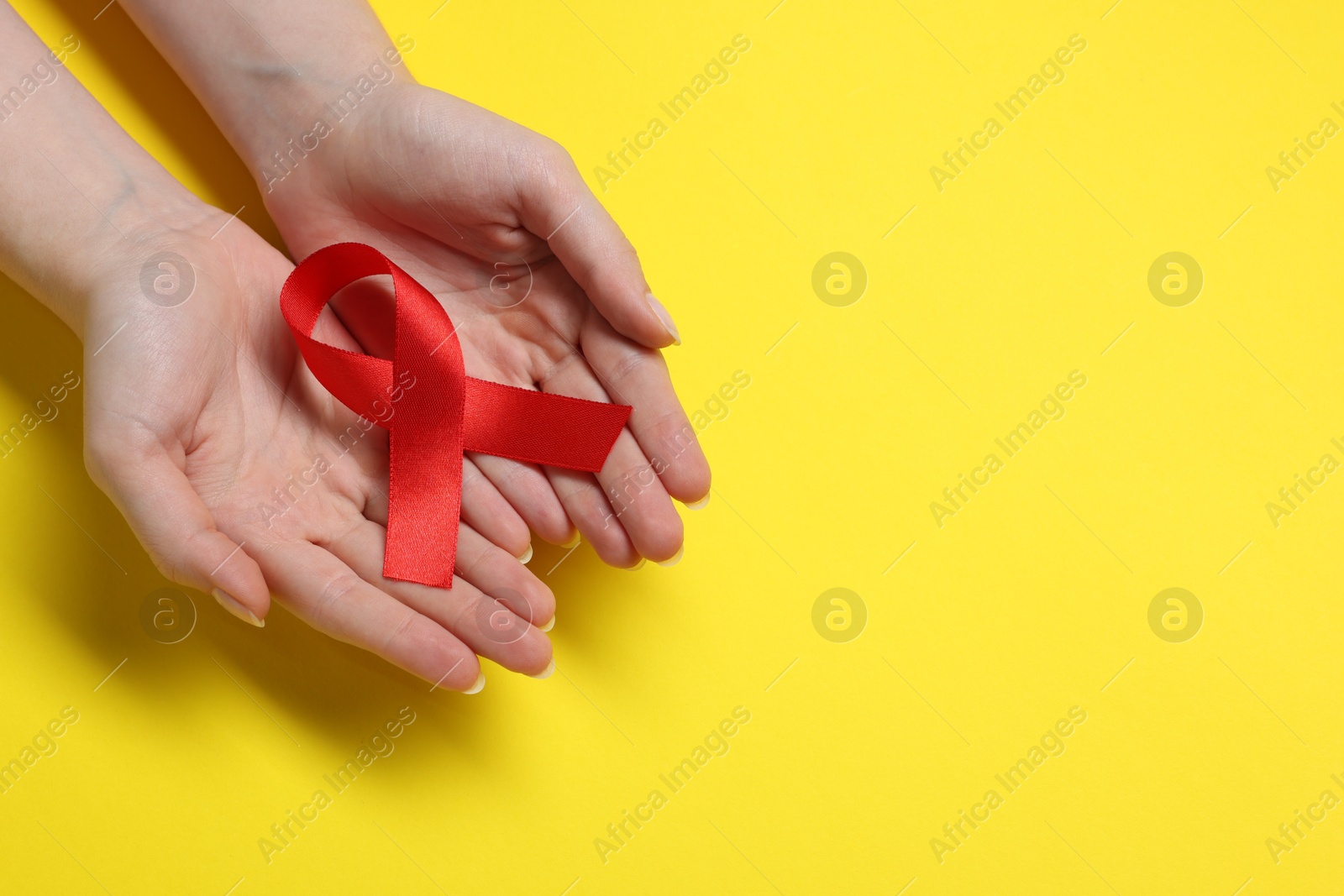 Photo of Woman with red ribbon on yellow background, top view and space for text. HIV (AIDS) disease awareness