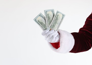 Photo of Santa Claus holding dollar banknotes on white background, closeup. Space for text