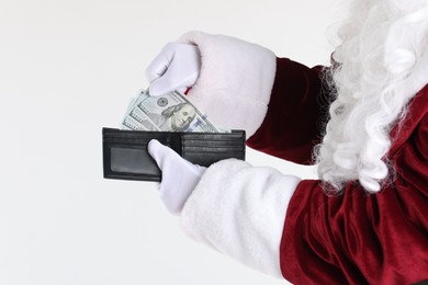 Photo of Santa Claus taking dollar banknotes out of wallet on white background, closeup