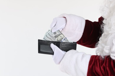 Photo of Santa Claus taking dollar banknotes out of wallet on white background, closeup. Space for text