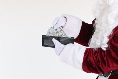 Santa Claus taking dollar banknotes out of wallet on white background, closeup. Space for text