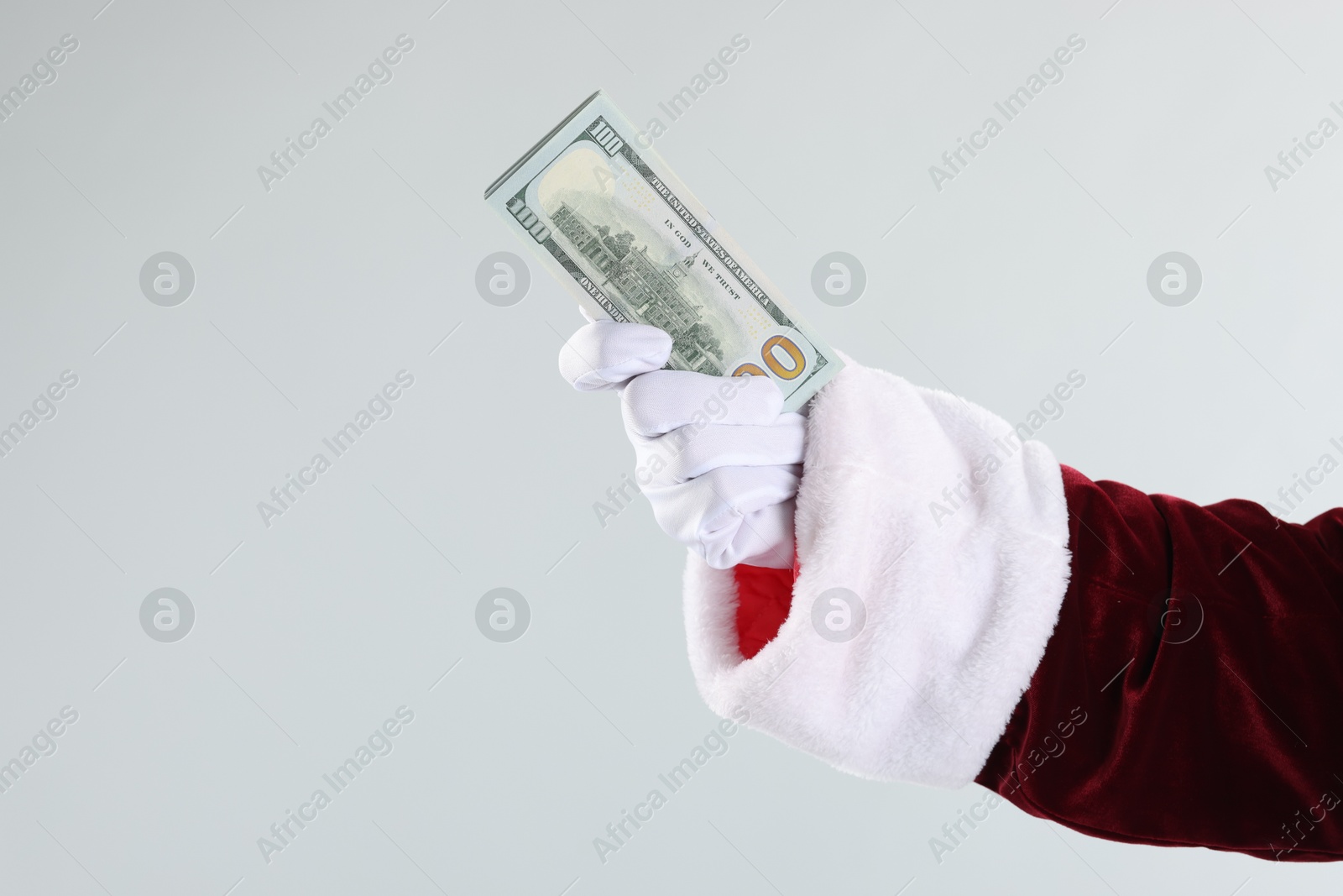 Photo of Santa Claus holding dollar banknotes on gray background, closeup. Space for text