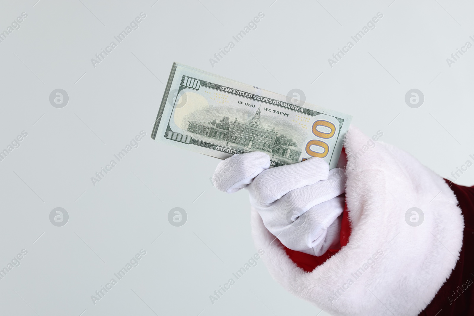 Photo of Santa Claus holding dollar banknotes on gray background, closeup. Space for text