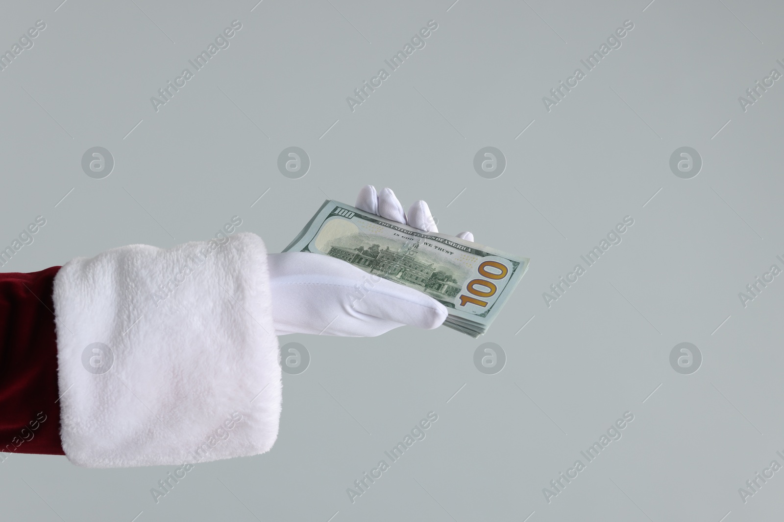 Photo of Santa Claus holding dollar banknotes on gray background, closeup. Space for text