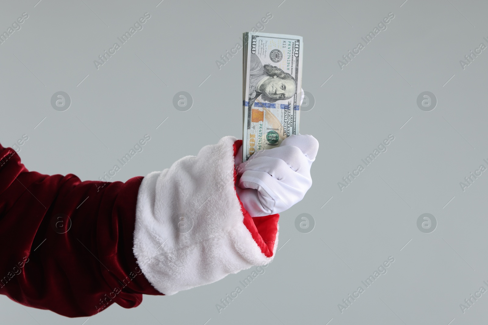 Photo of Santa Claus holding dollar banknotes on gray background, closeup. Space for text