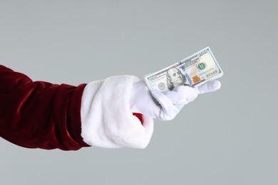 Photo of Santa Claus holding dollar banknotes on gray background, closeup