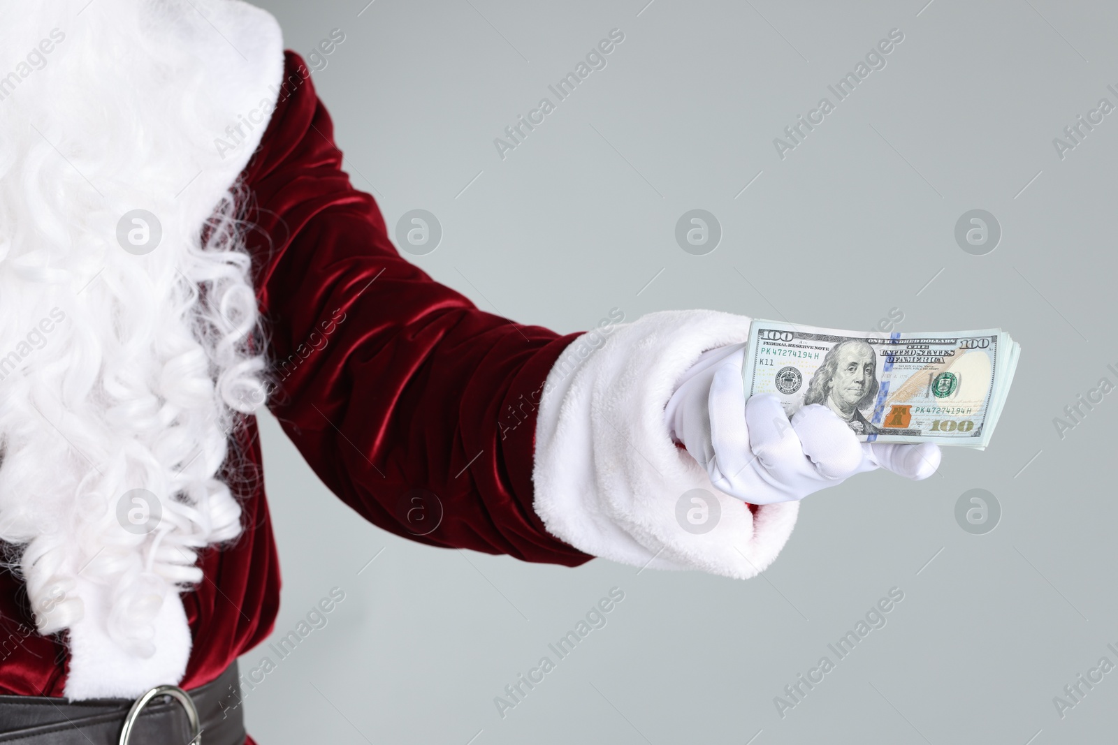 Photo of Santa Claus holding dollar banknotes on gray background, closeup