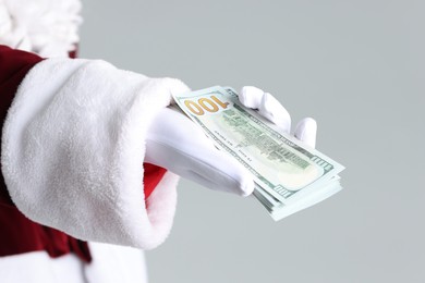 Photo of Santa Claus holding dollar banknotes on gray background, closeup