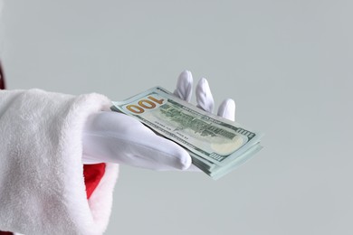 Photo of Santa Claus holding dollar banknotes on gray background, closeup