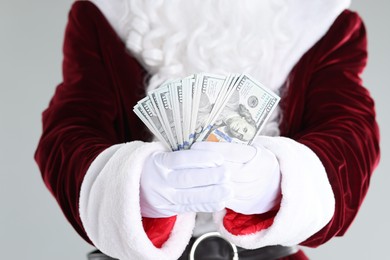 Photo of Santa Claus holding dollar banknotes on gray background, closeup