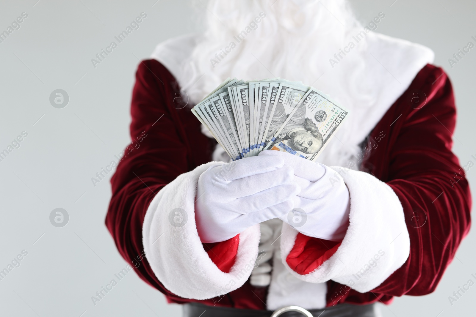 Santa Claus holding dollar banknotes on gray background, closeup Photo of Santa Claus holding dollar banknotes on gray background, closeup