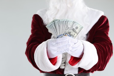 Photo of Santa Claus holding dollar banknotes on gray background, closeup