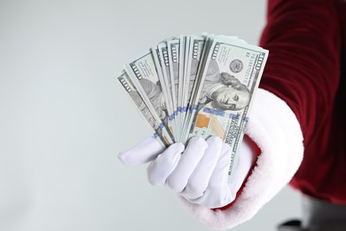 Photo of Santa Claus holding dollar banknotes on gray background, closeup. Space for text