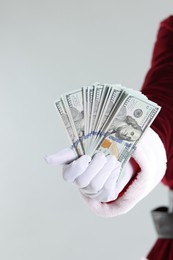 Photo of Santa Claus holding dollar banknotes on gray background, closeup