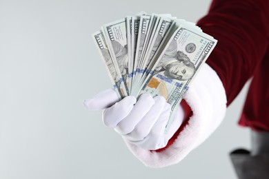 Photo of Santa Claus holding dollar banknotes on gray background, closeup. Space for text