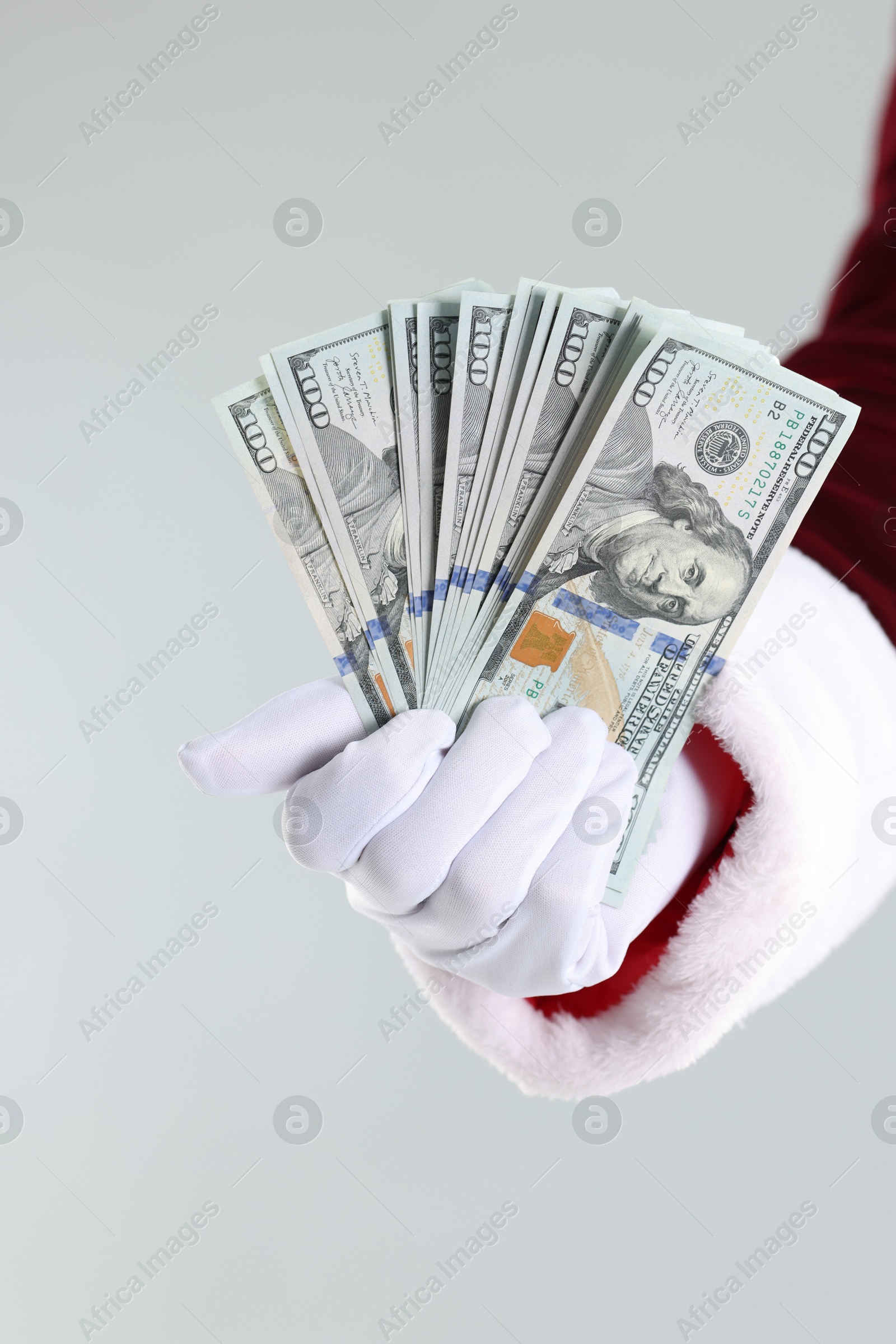 Photo of Santa Claus holding dollar banknotes on gray background, closeup