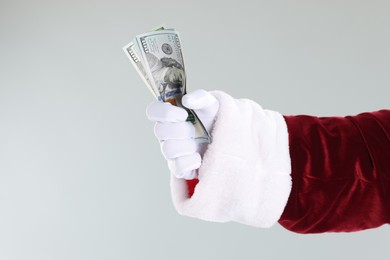 Photo of Santa Claus holding dollar banknotes on gray background, closeup