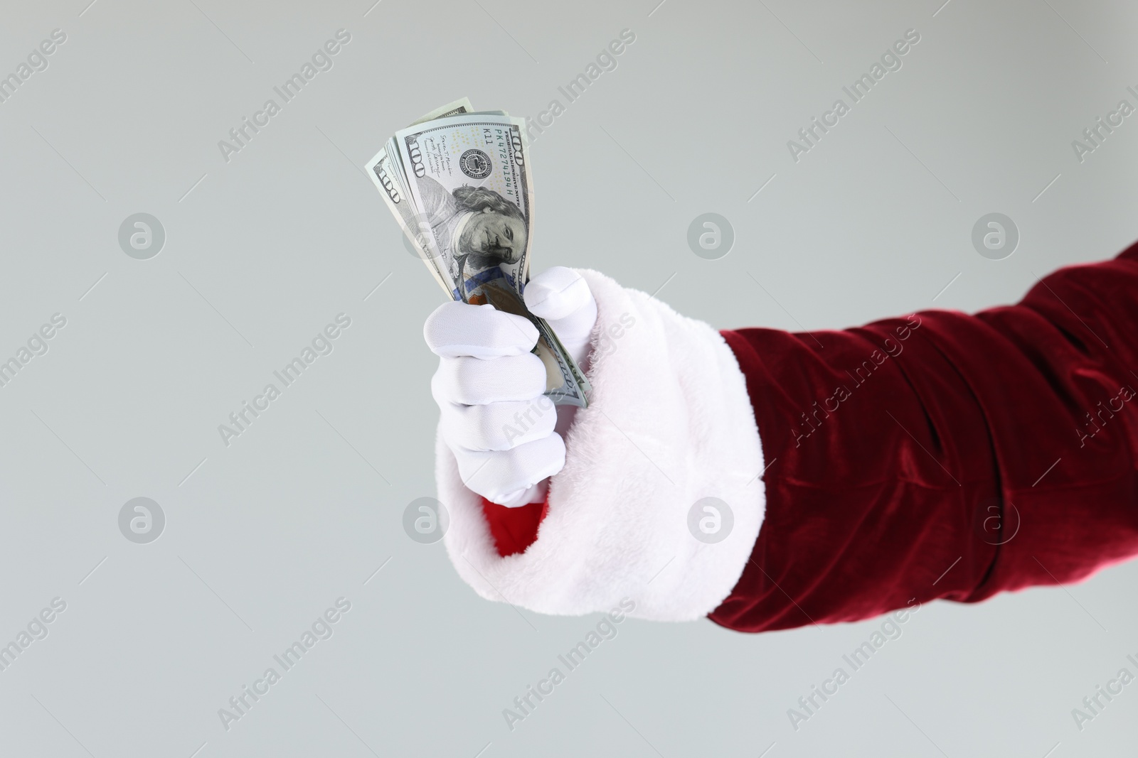 Photo of Santa Claus holding dollar banknotes on gray background, closeup