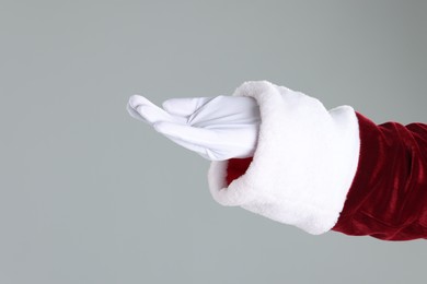 Photo of Santa Claus holding something on gray background, closeup. Space for text