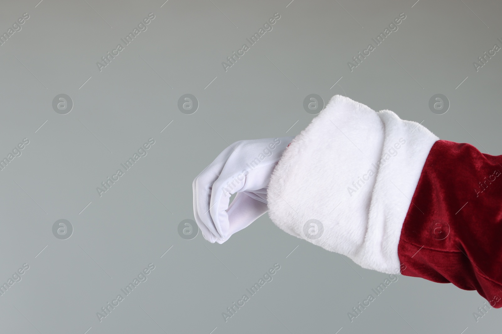 Photo of Santa Claus holding something on gray background, closeup. Space for text