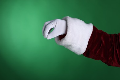 Photo of Santa Claus holding something on green background, closeup. Space for text