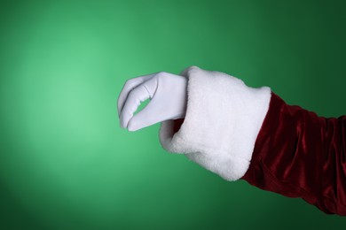 Photo of Santa Claus holding something on green background, closeup. Space for text