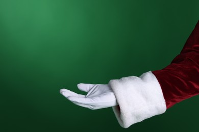 Photo of Santa Claus holding something on green background, closeup. Space for text