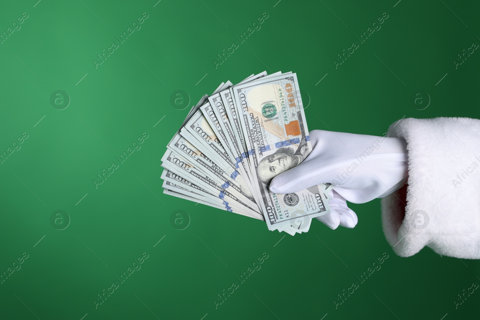 Santa Claus holding dollar banknotes on green background, closeup. Space for text Photo of Santa Claus holding dollar banknotes on green background, closeup. Space for text