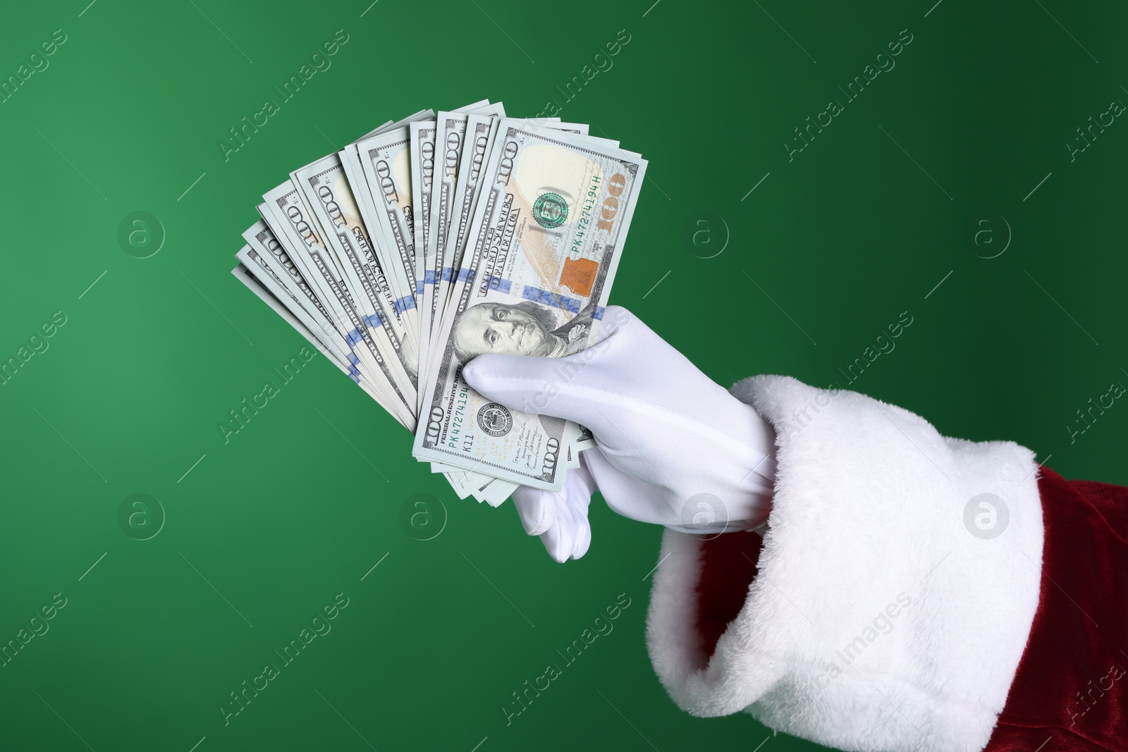 Photo of Santa Claus holding dollar banknotes on green background, closeup