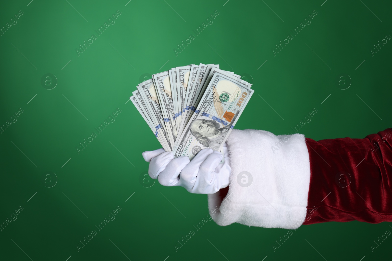 Santa Claus holding dollar banknotes on green background, closeup. Space for text Photo of Santa Claus holding dollar banknotes on green background, closeup. Space for text