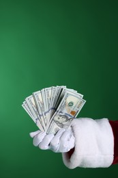 Photo of Santa Claus holding dollar banknotes on green background, closeup. Space for text