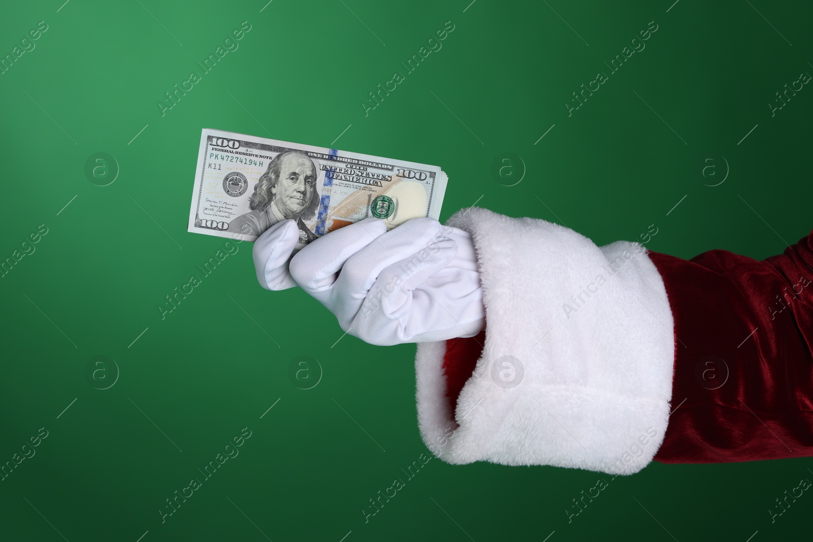 Photo of Santa Claus holding dollar banknotes on green background, closeup