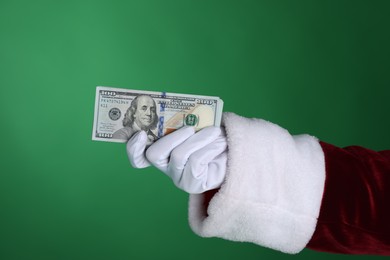 Photo of Santa Claus holding dollar banknotes on green background, closeup