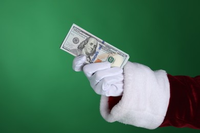 Photo of Santa Claus holding dollar banknotes on green background, closeup