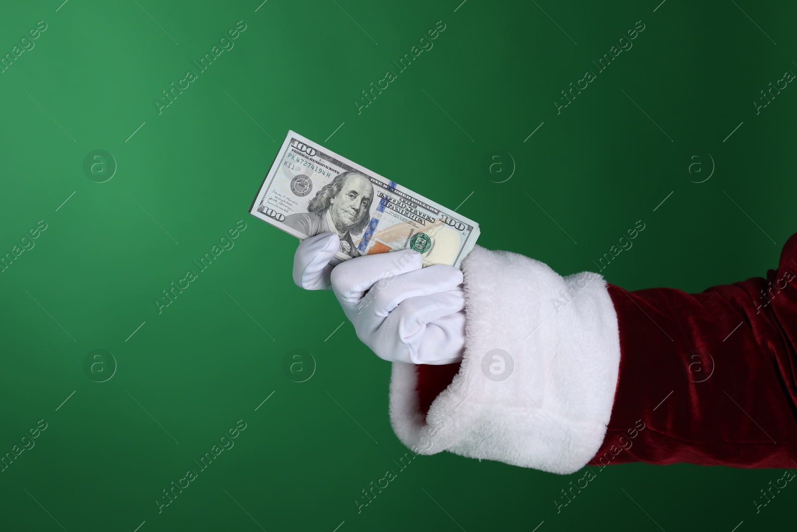 Santa Claus holding dollar banknotes on green background, closeup. Space for text Photo of Santa Claus holding dollar banknotes on green background, closeup. Space for text