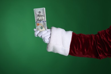 Photo of Santa Claus holding dollar banknotes on green background, closeup