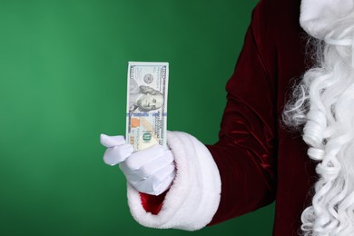 Photo of Santa Claus holding dollar banknotes on green background, closeup