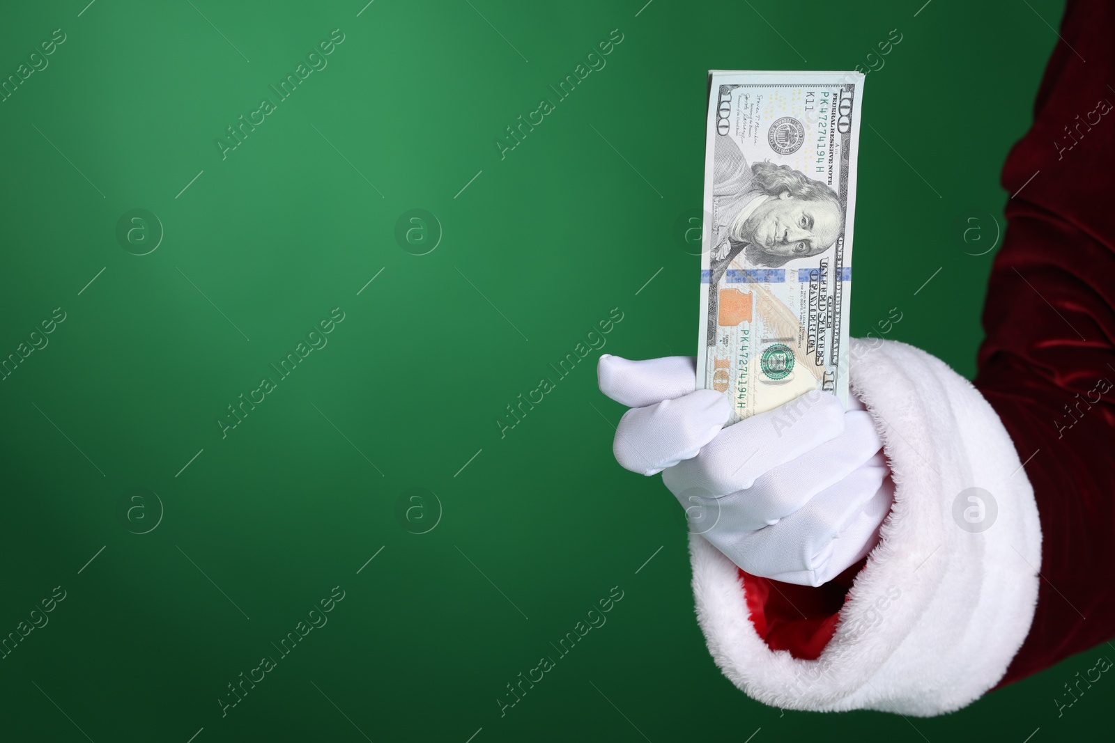 Photo of Santa Claus holding dollar banknotes on green background, closeup. Space for text