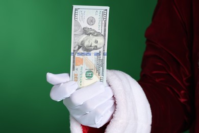 Photo of Santa Claus holding dollar banknotes on green background, closeup