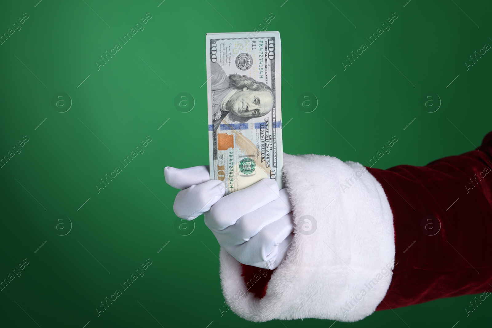 Photo of Santa Claus holding dollar banknotes on green background, closeup