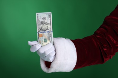 Photo of Santa Claus holding dollar banknotes on green background, closeup